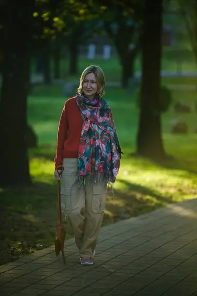 一个女人在公园的小巷里轻快地走着 她的神情坚定地注视着她在茂密的绿茵中的前路 图库图片