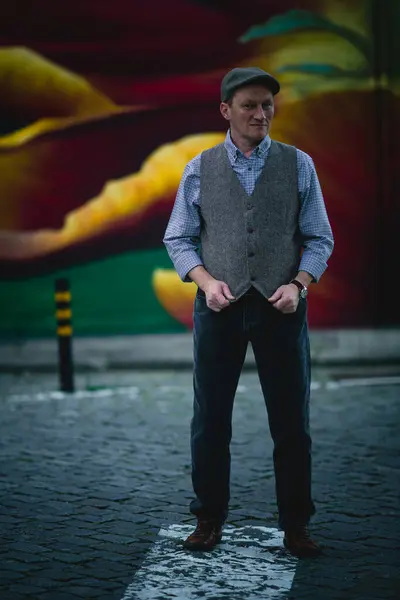 头戴便服的男人穿着便服的男人 包括帽子 牛仔裤和背心 站在一座古城的街道上 图库照片