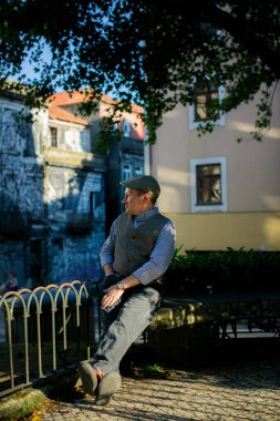 Orta yaşlı bir adam parkta oturur, huzur ve rahatlığın tadını çıkarır..