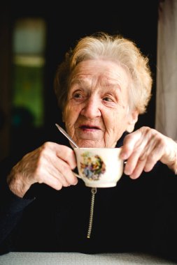Yaşlı bir kadın bir fincan çayın tadını çıkarır, huzurlu ve rahatlatıcı anın tadını çıkarır..