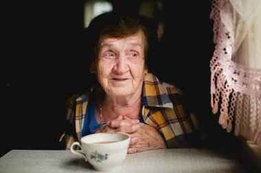 Evinde etkileyici bakışları olan yaşlı bir kadının portresi..