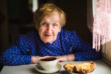 Evde çay içen nazik, yaşlı bir kadın..
