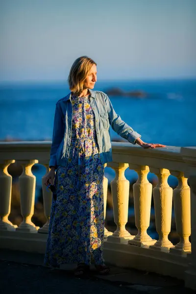 stock image A woman in a light dress on an oceanfront promenade in Portugal.