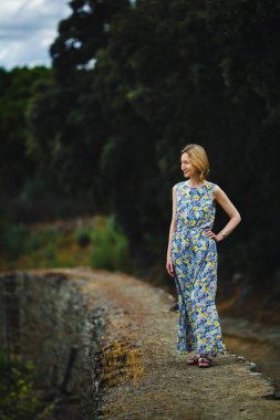 Portekiz 'in Douro Vadisi' nde, açık renk elbiseli bir kadın antik bir taş duvarın üzerinde duruyor..