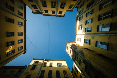 Saint Petersburg, Rusya 'da geleneksel bir avlu kuyusu manzarası. Kapalı, dar alan, gökyüzünün bir anlık görüntüsüyle yüksek tarihi binalar tarafından çerçevelenmiştir..