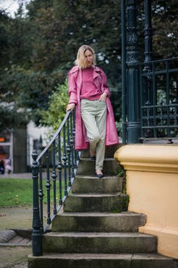 Pembe paltolu bir kadın parkta, bulutlu sonbahar havası sakin ve karamsar bir sahne yaratıyor..