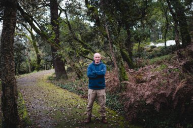 Sonbahar yapraklarının altın rengi ile çevrili, gözleri kapalı bir parkta duran bir adam huzur ve yansıma anının tadını çıkarıyor..