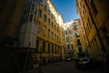 Eski Saint Petersburg avlusundan bir manzara, gökyüzüne bakıyor, yıpranmış, yıpranmış duvarlar ve aşağıda park edilmiş arabalar tarafından çerçevelenmiş.