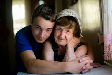 Genç yetişkin torunu tarafından kucaklanan yaşlı bir kadının yürek ısıtan portresi bir sevgi ve bağ anını yakalıyor..