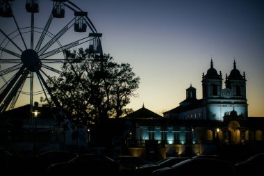Portekiz, Nazare 'de alacakaranlıkta bir tapınağın siluetleri ve dönme dolap..