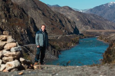 Rusya 'nın Altai Cumhuriyeti' nin dağlarında, engebeli bir manzarayla çevrili bir nehirde bir adam duruyor..