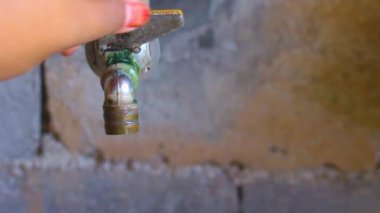 Ön manzara kadınları su musluğunu açar.