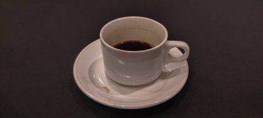 Siyah arka planda fincan tabağı olan siyah kahve lekeli beyaz fincan..