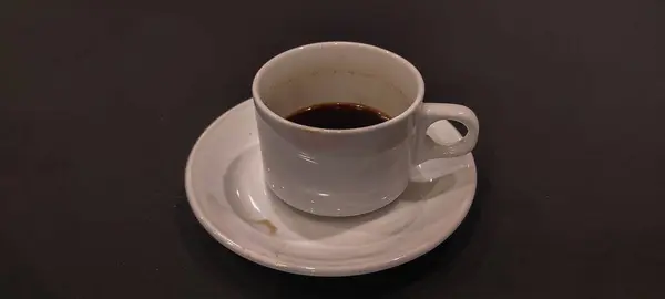 Siyah arka planda fincan tabağı olan siyah kahve lekeli beyaz fincan..