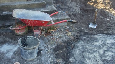 Kirli el arabası, çapa ve inşaat aletleri için siyah kumlara çarpmış. Aletleri olan inşaat alanı.