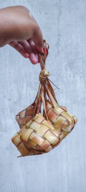 Endonezya ve Malezya 'daki Bayram kutlamaları sırasında sıklıkla şenliklere ve çok popüler yemeklere hazırlanan ketupat veya Güneydoğu Asya pirinç keki paketleri hazırlayan bir kadının eli
