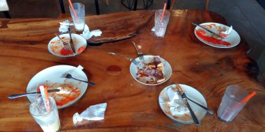 Yemek artıkları ve restoranın masasındaki kirli boş tabaklar. Öğle yemeği ya da akşam yemeğinin sonunu sembolize ediyor. Partiden sonra kalan artıklar..