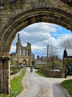 Byland Abbey kemerin arkasından motorsikletle yaklaşıyor.