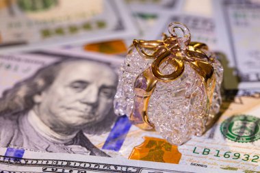 Tasarım amaçlı 100 dolarlık banknot zemininde altın kurdeleli cam hediye kutusu