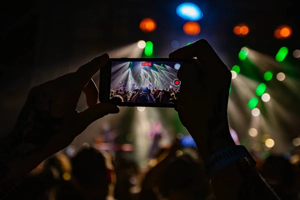 Hands holding phone and making photos on the concert. Concert background