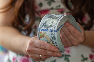 Kadın, tasarım amaçlı 100 dolarlık banknotları tutuyor.