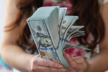 Kadın, tasarım amaçlı 100 dolarlık banknotları tutuyor.
