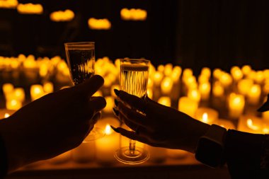 Sahnedeki senfonik orkestranın arka planında şarap kadehleri ve dizayn amaçlı bir sürü mum var.