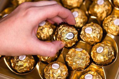 İtalya - 6 Aralık 2024: Ferrero Rocher altın parıltılı arka planda özel çikolata