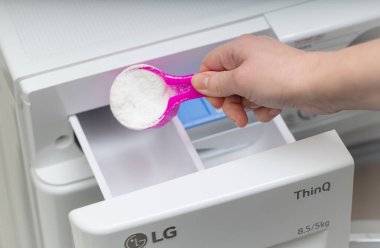 Lviv, Ukrayna - 20 Aralık 2024: LG ThinQ çamaşır ve kurutma makinesine el deterjanı dökme