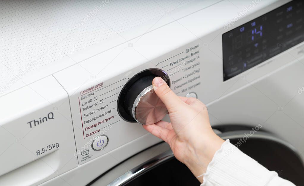 Lviv, Ukraine - December 20, 2024: hand turning on LG ThinQ washing and drying machine