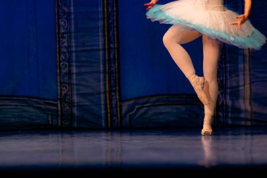 Sahnede yapayalnız dans eden balerinin yakın çekimi. Balerin bacakları yakın plan