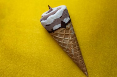 Çikolatalı dondurma külahı ve altın arka planda Vanilya Girdabı