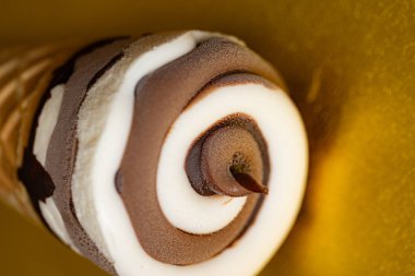 Çikolatalı dondurma külahı ve altın arka planda Vanilya Girdabı