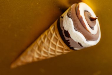 Çikolatalı dondurma külahı ve altın arka planda Vanilya Girdabı