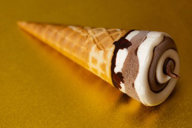 Çikolatalı dondurma külahı ve altın arka planda Vanilya Girdabı