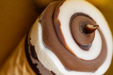 Çikolatalı dondurma külahı ve altın arka planda Vanilya Girdabı