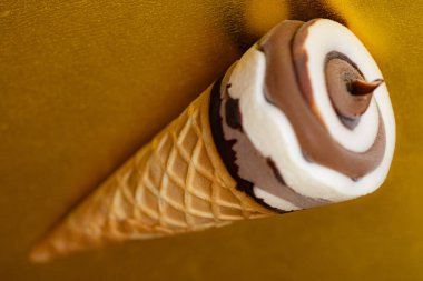 Çikolatalı dondurma külahı ve altın arka planda Vanilya Girdabı