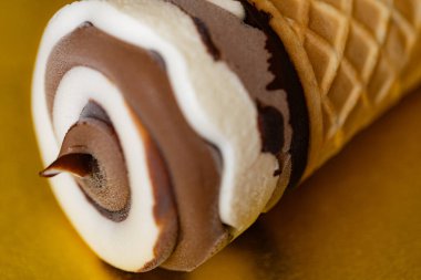 Çikolatalı dondurma külahı ve altın arka planda Vanilya Girdabı