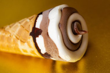 Çikolatalı dondurma külahı ve altın arka planda Vanilya Girdabı