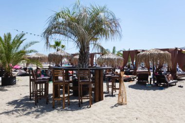 Tahta masası ve palmiye ağaçları olan sahil barı.