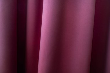 Pembe bir perdeye yakın çekim, parlak bir yüzey, yumuşak kıvrımlar ve hafif bir ışık ve gölge gradyanı yaratır.