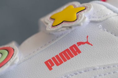 Lviv, Ukrayna - 24 Ağustos 2025: Renkli yamalı, arka planda kırmızı ayakkabı kutusu olan yeni bir çift beyaz çocuk ayakkabısı.