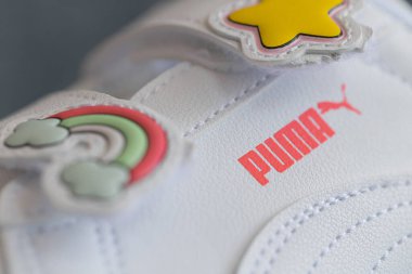 Lviv, Ukrayna - 24 Ağustos 2025: Renkli yamalı, arka planda kırmızı ayakkabı kutusu olan yeni bir çift beyaz çocuk ayakkabısı.