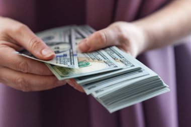 Yüz dolarlık banknotları tutan ve sayan bir insan..