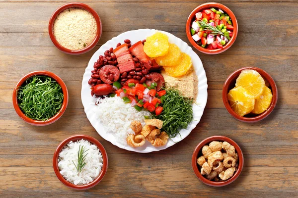 stock image Brazilian feijoada, traditional food from Brazil cuisine, on white plate, over rustic wooden table. top view