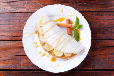 Ev yapımı tapyoka ya da muz ve yoğunlaştırılmış sütle doldurulmuş Beiju ya da ahşap masa üzerinde malt karamel. en üstteki görünüm