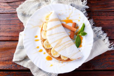 Ev yapımı tapyoka ya da muz ve yoğunlaştırılmış sütle doldurulmuş Beiju ya da ahşap masa üzerinde malt karamel. en üstteki görünüm