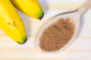 Ahşap kesme tahtasının üzerinde muz ve tarçın tozu var. Sağlıklı doğal atıştırmalıklar. en üstteki görünüm