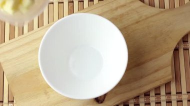 Kesme tahtasındaki beyaz seramik kaseye yerleştirilmiş mozzarella peyniri küpleri. Üst görünüm