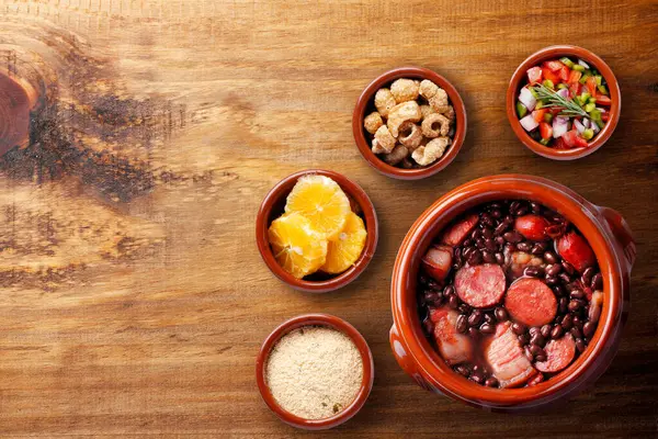 stock image Brazilian feijoada, traditional food from Brazil cuisine, on ceramic casserole bowl, over rustic wooden table. top view